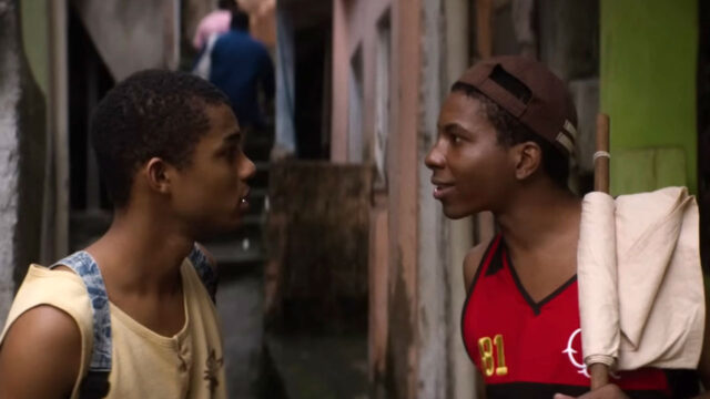Juan Paiva como Buchecha e Lucas Penteado como Claudinho conversando em viela de comunidade em cena do filme Nosso Sonho