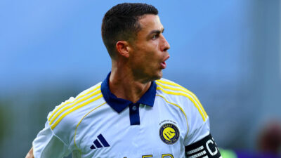 Cristiano Ronaldo em campo usando uniforme branco e amarelo do Al Nassr com faixa de capitão no braço esquerdo