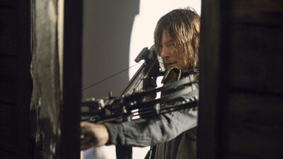 Norman Reedus como Daryl Dixon mirando com besta em cena da série The Walking Dead