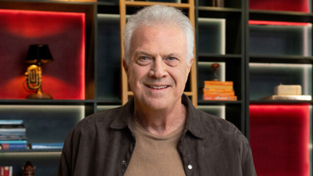 Pedro Bial em ambiente interno, posicionado à frente de estante com livros e objetos decorativos.