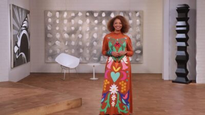 Adriana Couto de vestido longo laranja com estampa viva posa sorrindo no novo cenário do Metrópolis da TV Cultura