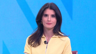 Carol Nogueira com blusa amarela apresentando telejornal no estúdio da CNN Brasil