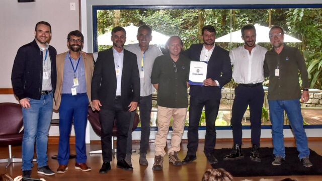 Representantes da Globo e do INEA posam sorrindo após firmarem parceria em evento oficial