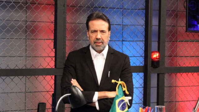 Jorge Lorello de terno preto com braços cruzados no cenário do programa Operação de Risco