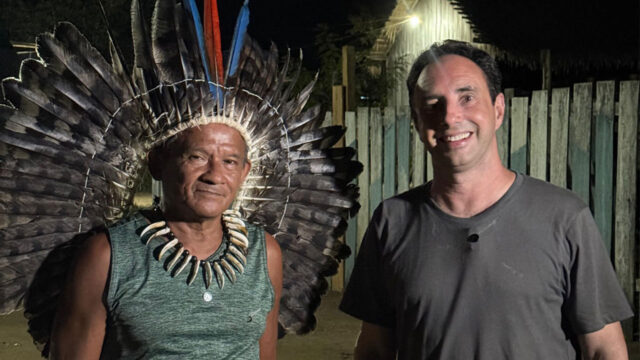 Cacique Joaquim Alves Rodrigues, da Aldeia Esperança, com cocar de penas posa ao lado do repórter Pedro Bassan em série do Jornal Nacional