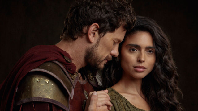Elisa (Nathalia Florentino) olha para a câmera enquanto é abraçada por Caius (Dudu Pelizzari) em foto de O Senhor e a Serva
