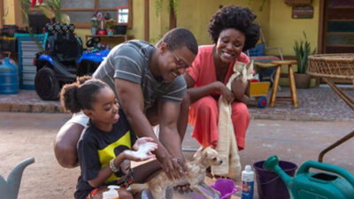 Dandara Arcebispo e David Junior dão banho em um cão, enquanto Luellem de Castro observa sorrindo em cena do filme Roubo do Cão