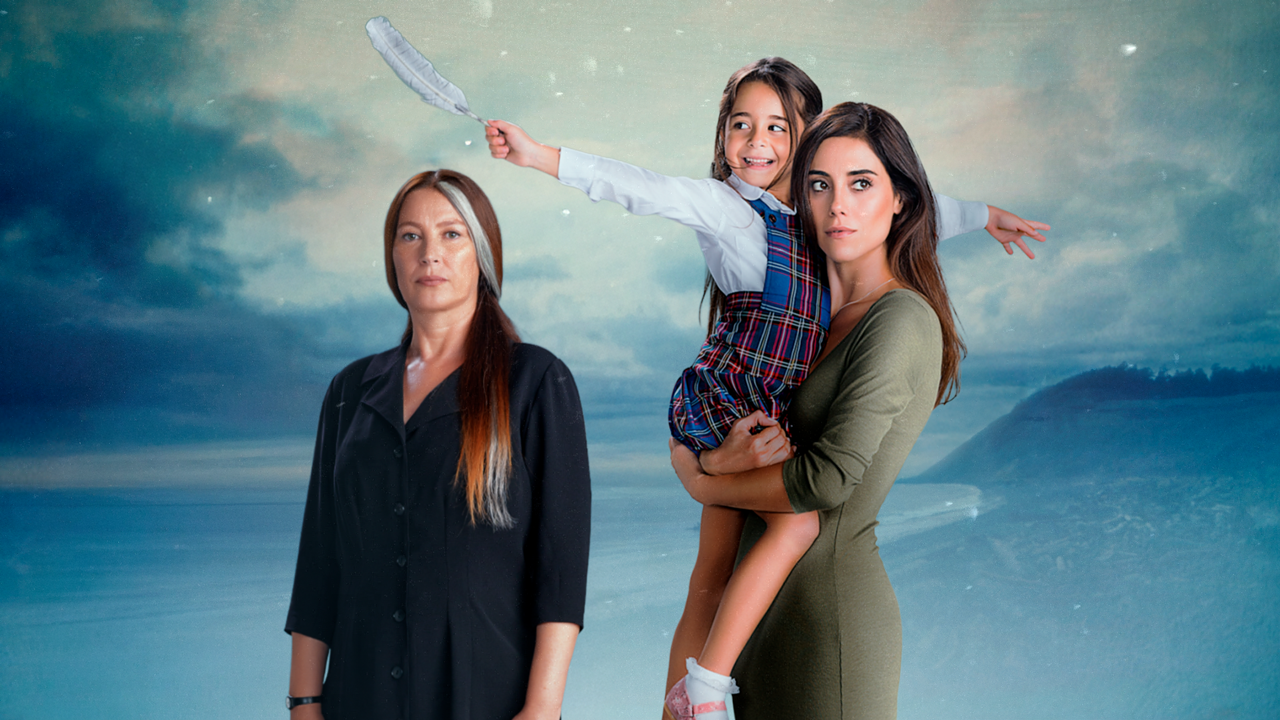 Mulher de expressão séria de roupa preta ao lado de mulher segurando menina sorridente com uniforme escolar e pena branca na mão diante de paisagem azul com céu nublado