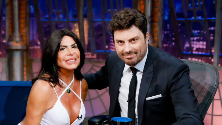 A cantora Gretchen com top branco e Danilo Gentili de terno e gravata posam juntos para foto no estúdio do The Noite, no SBT