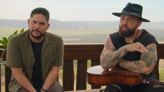 Jorge e Matheus sentados em varanda com paisagem rural ao fundo durante gravação do programa Viver Sertanejo