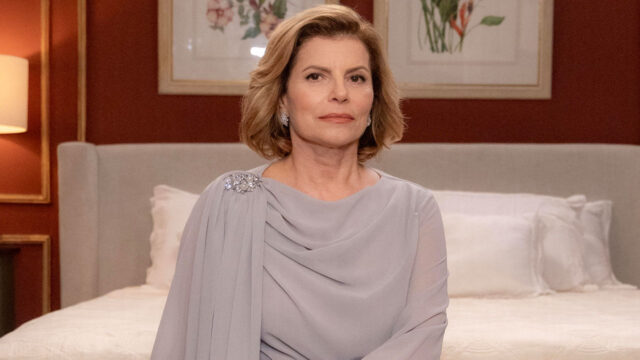 Débora Bloch como Odete Roitman com vestido elegante e expressão séria no quarto luxuoso do set de Vale Tudo