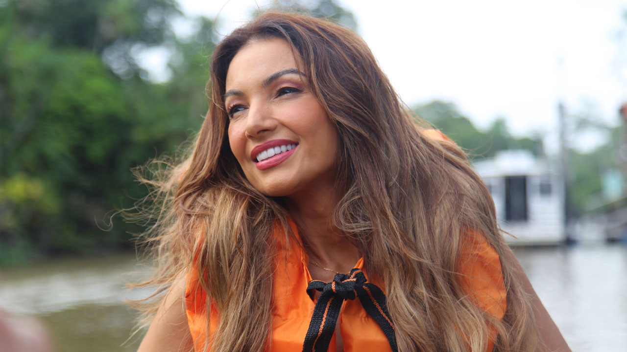 Patrícia Poeta usa colete salva-vidas laranja em barco sobre rio em Belém com vegetação ao fundo