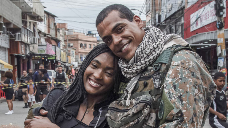 Sarah (Erika Januza) e Mikhael (Marcello Melo Jr.) abraçados em rua de comunidade em cena da série Arcanjo Renegado