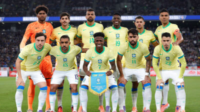 Jogadores da seleção brasileira de futebol posam com a camisa amarela e calções brancos no campo antes de amistoso contra o Japão