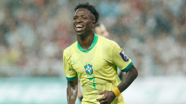 Vini Jr. sorri sob chuva durante amistoso da seleção brasileira contra a Coreia do Sul vestindo camisa amarela da CBF