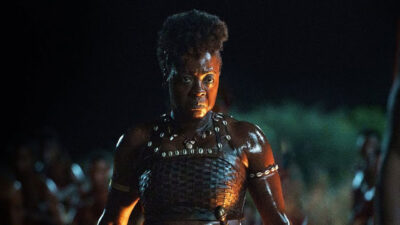 Viola Davis como a general Nanisca com roupas de guerreira e expressão séria em cena noturna do filme A Mulher Rei