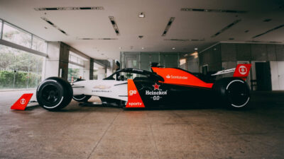 Carro réplica da Fórmula 1 preto, branco e laranja com logos da Globo, SporTV e Globoplay, em exposição no prédio da emissora