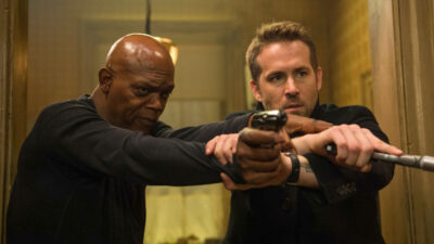 Samuel L Jackson (Darius) e Ryan Reynolds (Michael) armados, apontando pistolas em cena do filme Dupla Explosiva