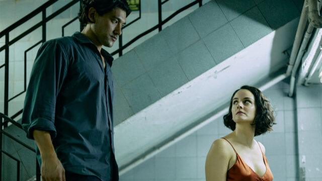 Emmanuelle (Noémie Merlant) e Kei Shinohara (Will Sharpe) se encaram em uma escadaria de azulejos claros em cena do filme Emmanuelle