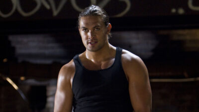 Jason Momoa como Keegan usando regata preta, olhando fixamente para a câmera em cena do filme Alvo Duplo