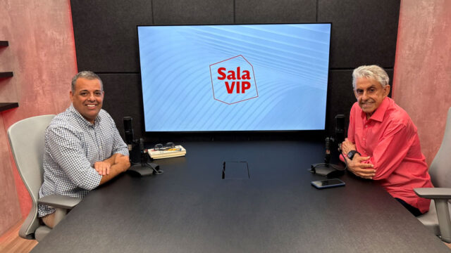 Luciano Calheiros e Roberto Alves em estúdio de podcast sentados à mesa, com o logo Sala VIP em tela ao fundo da bancada