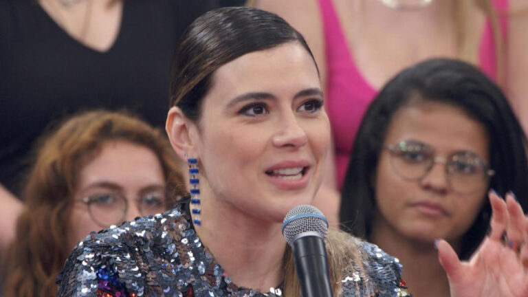 Jornalista Michelle Loreto sorrindo, usando roupa de lantejoulas e brinco comprido em participação no Altas Horas