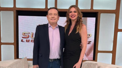 Roberto Cabrini de terno e Luciana Gimenez de vestido preto posam juntos no palco do programa SuperPop na RedeTV
