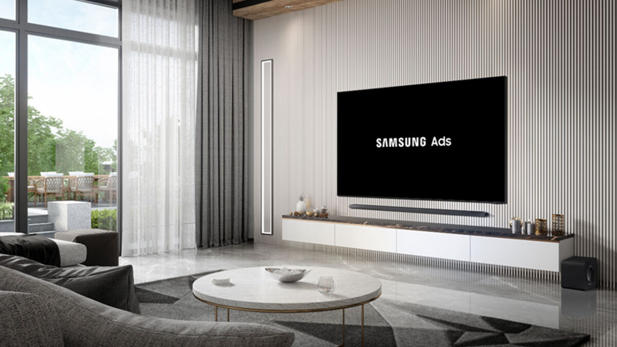 Smart TV da Samsung em uma sala de estar moderna exibindo o logotipo da Samsung Ads em branco na tela preta