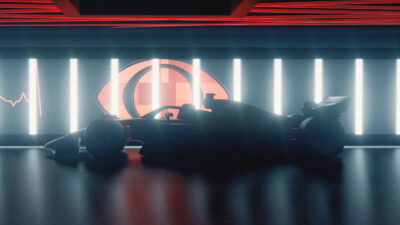 Carro de Fórmula 1 corre em alta velocidade na pista com logotipos da Band visíveis nas placas de publicidade ao fundo da imagem