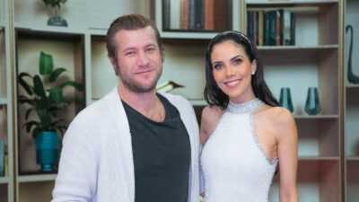 Diego Alemão de cardigã e Daniela Albuquerque com top brilhante sorriem lado a lado no cenário do programa Sensacional da RedeTV!