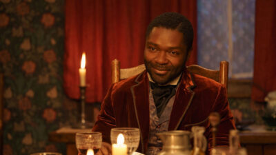 Ator David Oyelowo sorrindo como Jack Littleton, vestindo terno de veludo vermelho, à luz de velas em Alice e Peter