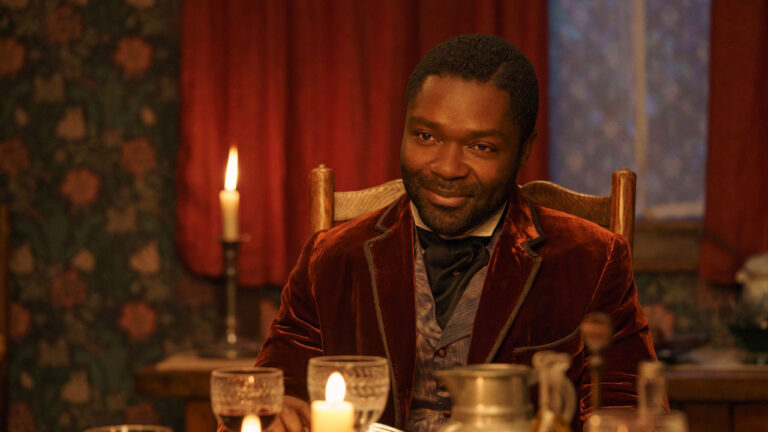 Ator David Oyelowo sorrindo como Jack Littleton, vestindo terno de veludo vermelho, à luz de velas em Alice e Peter