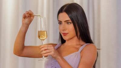 Jade Picon como a vilã Soraia colocando líquido em taça de champanhe em cena da novela Tudo por Uma Segunda Chance