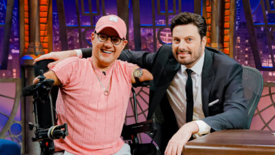 Marcos Rossi e o apresentador Danilo Gentili sorrindo juntos em poltronas durante entrevista no cenário do The Noite