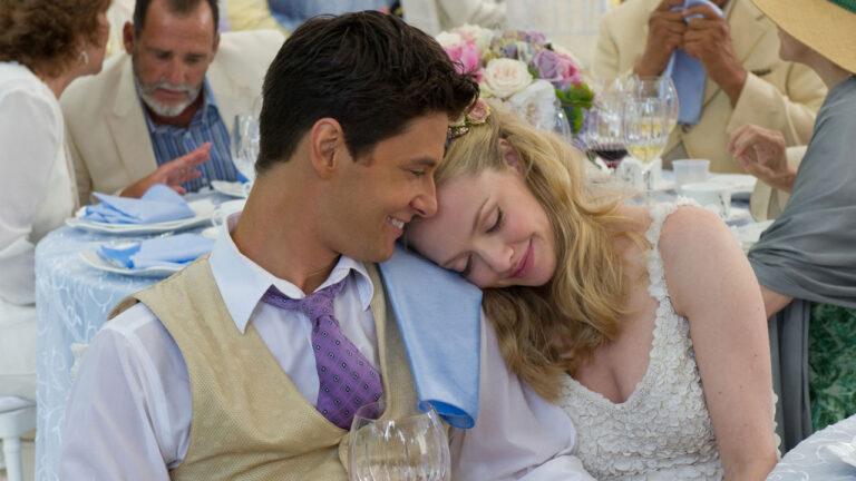 Missy (Amanda Seyfried) sorri e apoia a cabeça em Alejandro (Ben Barnes) na festa de casamento no filme O Casamento do Ano