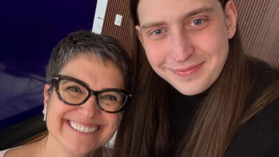 Sandra Annenberg de óculos sorri ao lado do influenciador Felca de cabelos longos em selfie para o programa Globo Repórter
