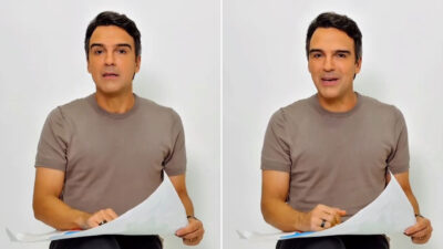 Tadeu Schmidt veste camiseta bege e segura papéis ao sorrir para a câmera em vídeo sobre a nova temporada do Big Brother Brasil