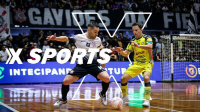 Jogador do Corinthians disputa bola com adversário em jogo de futsal com logotipo da Xsports sobreposto e torcida ao fundo