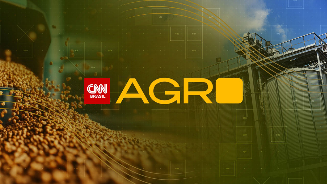 Logotipo do CNN Agro ao centro sobre imagem de grãos de soja e silos de armazenamento representando o agronegócio brasileiro