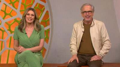 Cristina Vieira e Nélson Araújo sorrindo sentados no cenário do Globo Rural com fundo laranja e verde durante o dominical da Globo