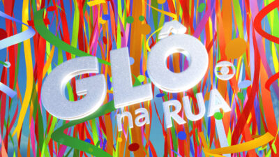 Logotipo prateado Glô na Rua com textura de glitter entre muitas fitas coloridas verticais na cobertura de Carnaval da TV Globo