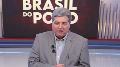 José Luiz Datena de paletó cinza no cenário do programa Brasil do Povo na RedeTV com logotipo da atração em destaque no telão ao fundo