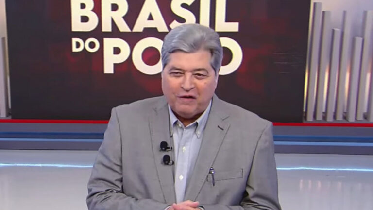 José Luiz Datena de paletó cinza no cenário do programa Brasil do Povo na RedeTV com logotipo da atração em destaque no telão ao fundo