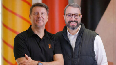 Marcelo Pacheco e Eduardo Boschetti posam sorridentes para foto institucional da Eletromidia