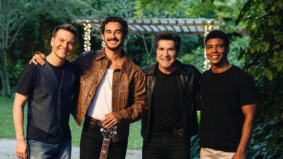 Michel Teló, João Raul interpretado por Filipe Bragança, Daniel e Luan vivido por Lucas Wickhaus sorrindo juntos nos bastidores de gravação de Coração Acelerado em sítio