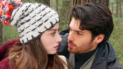 Nazli (Ozge Gurel) com gorro de lã e Ferit Aslan (Can Yaman) se olham intensamente em cena da novela turca Dolunay na floresta