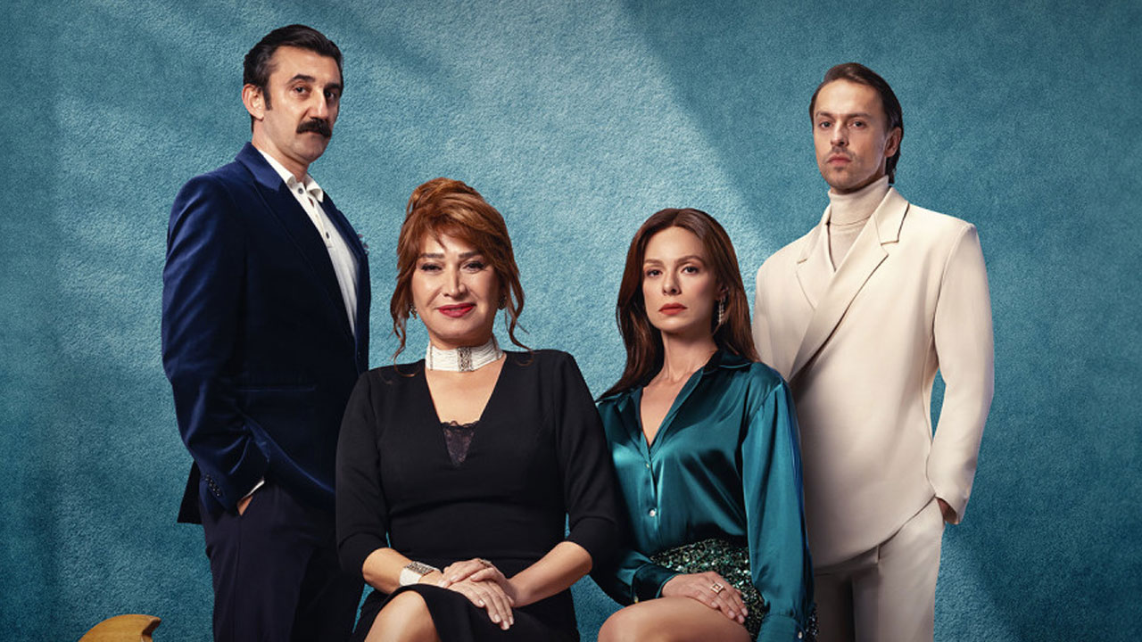 Elenco principal da novela turca Coração de Mãe (I Am Mother) posa unido com roupas elegantes em tons de azul, preto e branco sobre fundo azulado