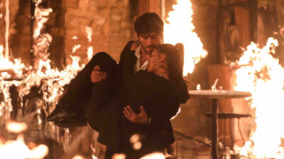 Omer (Cihangir Ceyhan) carrega Ruya (Dilan Cicek Deniz) nos braços para salvá-la de um grande incêndio na novela Chamas do Destino