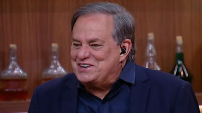 Ronnie Von sorridente com terno azul marinho e fone de ouvido durante a gravação do programa Companhia Certa nos estúdios da RedeTV
