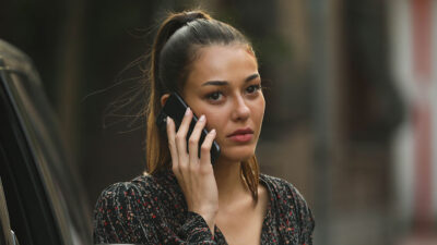 Dilan Cicek Deniz como a personagem Ruya com expressão séria enquanto fala ao celular em cena da novela turca Chamas do Destino